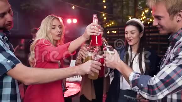快乐的年轻人在聚会上玩得很开心在朋友聚会上用五颜六色的饮料碰瓶子视频的预览图