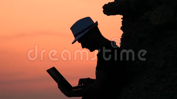 准备投球男性自由职业者hipster与笔记本电脑远程工作在海滩上的日落雇员背景视频的预览图