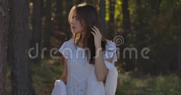 神秘的高加索女人站在阳光下的森林里四处张望穿浅白色连衣裙的漂亮女孩视频的预览图