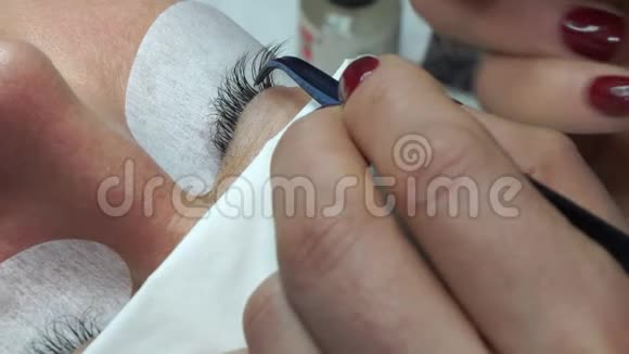 用镊子粘合人造睫毛化妆程序睫毛延伸长睫毛的女人眼视频的预览图