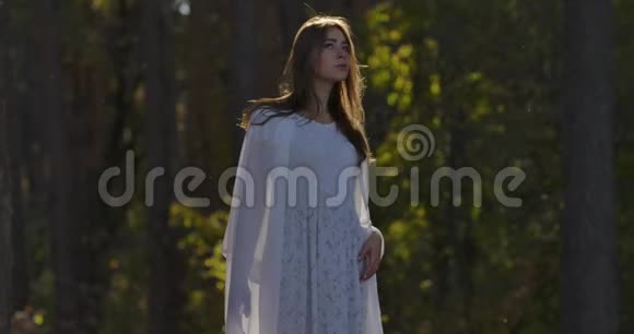可爱的白种人女孩站在森林里的阳光下仰望穿着白色长裙的漂亮女人视频的预览图