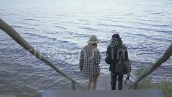年轻的白种人夫妇走下楼梯来到小码头朋友们一起在户外玩视频的预览图