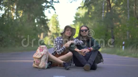 年轻的白种人夫妇坐在路上的森林背景戴草帽的女人戴草帽的男人视频的预览图