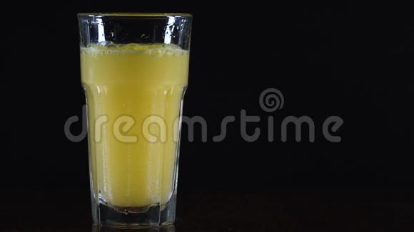 橙色饮料在玻璃杯里黑色背景上的玻璃片剂溶于水视频的预览图
