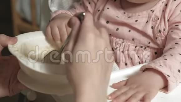 妈妈在一张高椅子上喂一个小女孩视频的预览图