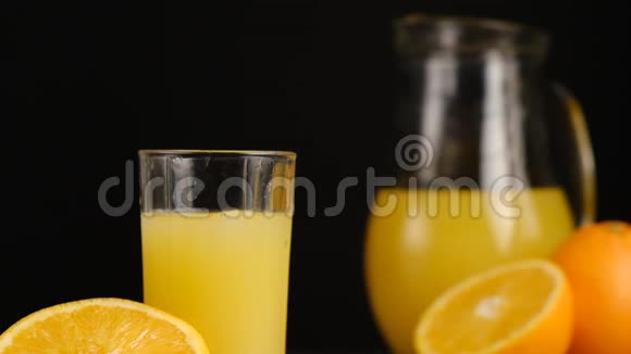 冰块落在一杯橙汁或柠檬水中上面有橘子和水罐视频的预览图