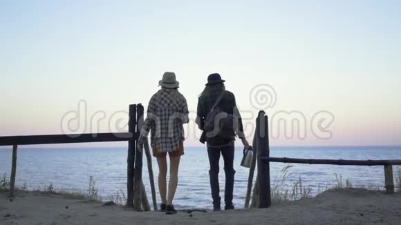 穿着格子衬衫的希普斯特千禧旅游夫妇在海滩上在大海和风景如画的背景下聊天视频的预览图