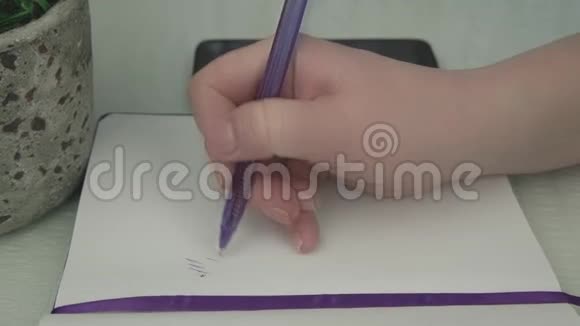 年轻女子用紫色钢笔在笔记本上写字视频的预览图