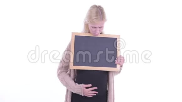 穿着衣服的年轻金发孕妇拿着黑板听到坏消息视频的预览图
