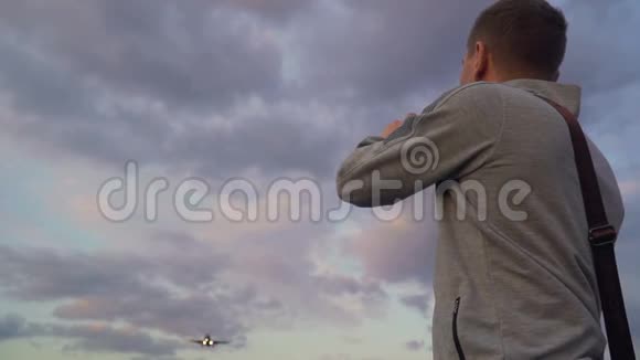 青年拍飞机在傍晚云天飞行的照片使用智能手机视频的预览图