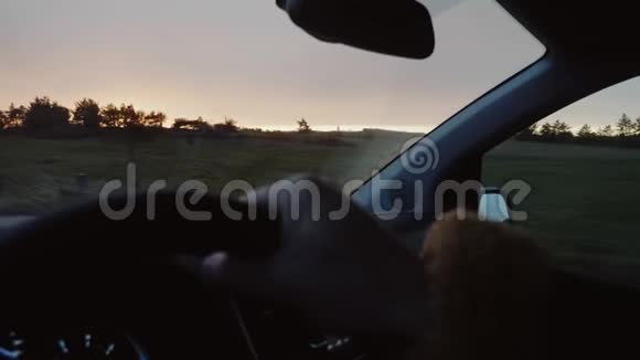 POV特写镜头男性手握汽车方向盘沿着壮丽的秋日夕阳乡村道路缓慢行驶视频的预览图