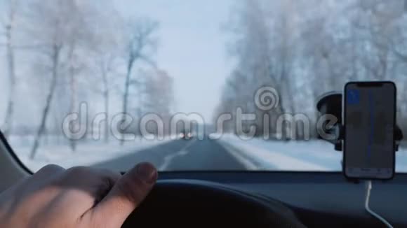 Pov特写男手握车方向盘沿着雪冬路行驶智能手机导航慢动作视频的预览图