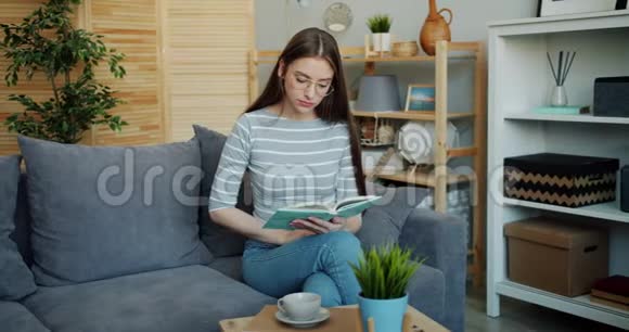 公寓沙发上严肃的女士阅读书的肖像集中在活动上视频的预览图