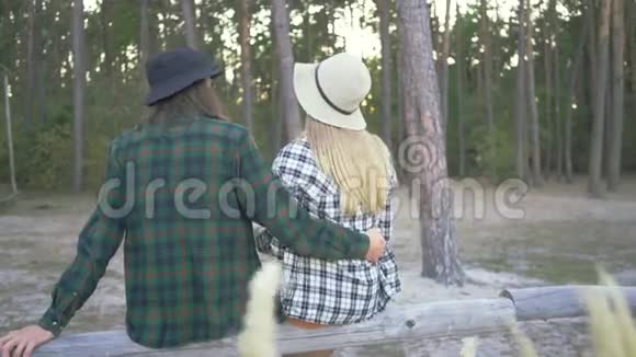 游客夫妇坐在森林里穿着格子衬衫和帽子年轻的白种人女孩正在喝茶视频的预览图