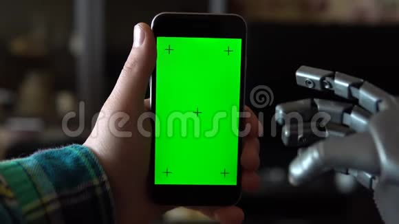 赛博格用电话灰色机械手刷左智能手机与绿色屏幕铬钥匙视频的预览图