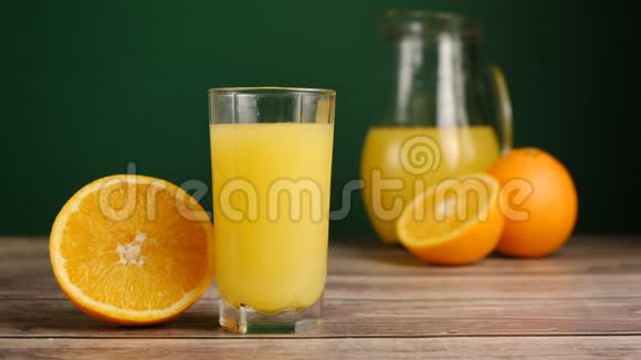 冰块倒在一杯橙汁或柠檬水中放在带有橘子的木桌上视频的预览图
