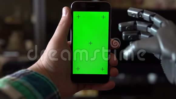 赛博格用电话灰色机械手正在用绿色屏幕在智能手机上打字铬钥匙视频的预览图
