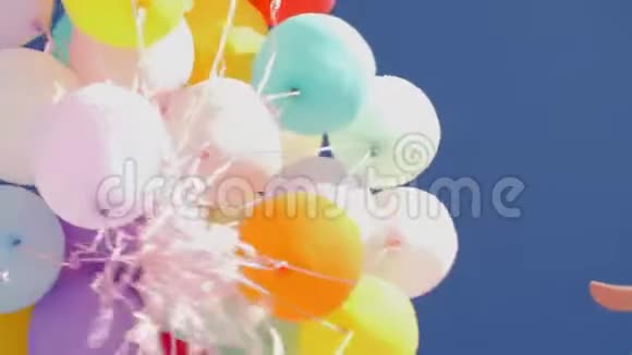 五颜六色的球在晴朗的蓝天中飞走了在蓝天上发射充气气球视频的预览图