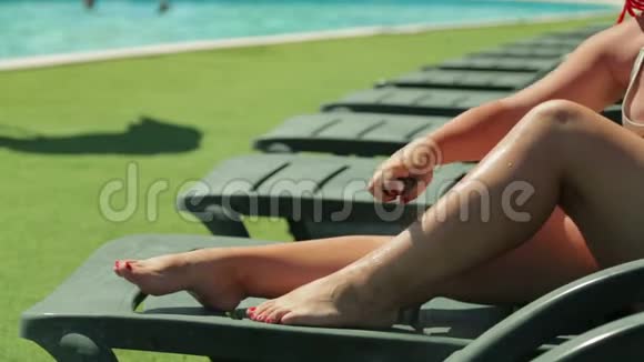 泳池边的躺椅上有个女人涂了防晒霜视频的预览图