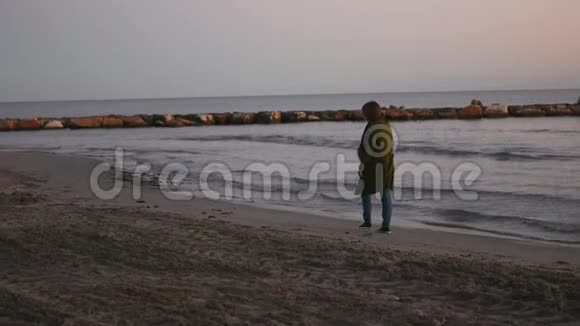 日落时年轻女子正在海滩上散步慢动作视频的预览图