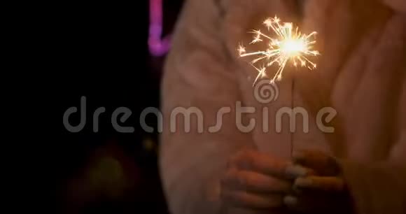 年轻女人手中的火花火花在霓虹灯背景下向不同方向散射视频的预览图