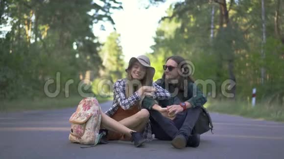 千禧一代游客幸福的一对穿着格子衬衫拥抱着一起坐在路上旅行视频的预览图