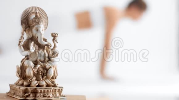 Ganesha雕像和不可辨认的女性走出重点区域练习瑜伽视频的预览图