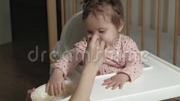 妈妈在一张高椅子上喂一个小女孩视频的预览图