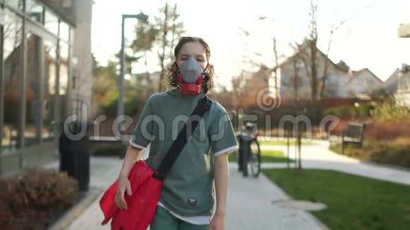 戴着呼吸器带着一个红色袋子的男孩在街上走着欧洲国家的检疫冠状病毒视频的预览图