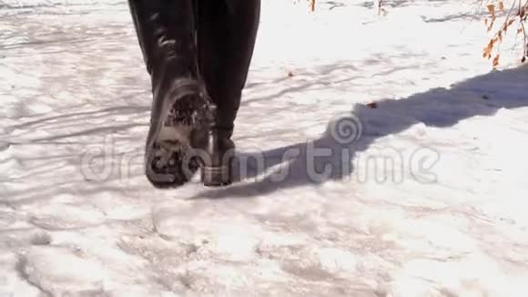 穿着冬靴在雪地上行走的女人的侧视视频的预览图