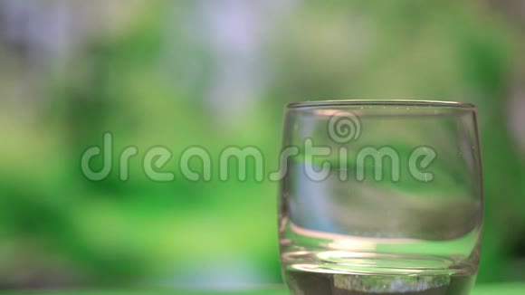在模糊的绿色背景下将新鲜牛奶倒入玻璃杯中视频的预览图