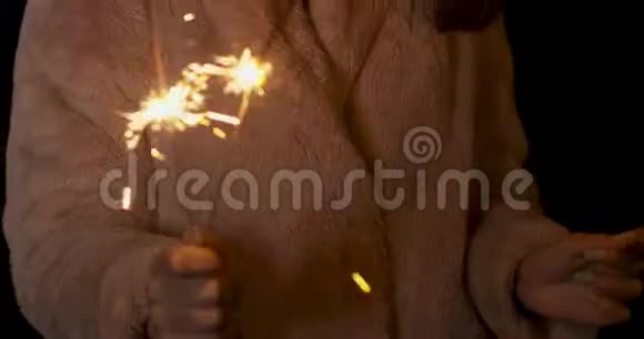 年轻女人手中的火花火花在霓虹灯背景下向不同方向散射视频的预览图