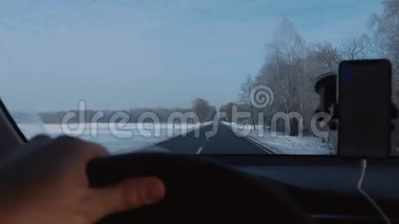 POV特写镜头司机驾驶汽车在华丽的冬季道路与智能手机导航应用程序慢动作视频的预览图