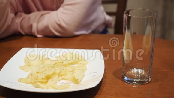 青少年的手从盘子里拿薯片把可乐倒进玻璃里人们吃土豆酥和碳酸水视频的预览图