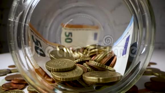 货币储蓄在装满欧元硬币和钞票的玻璃瓶中滑动视频的预览图