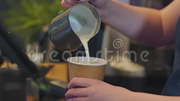 女咖啡师把热牛奶和泡沫倒入纸玻璃中视频的预览图