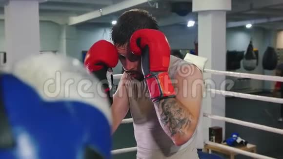 拳击训练两个汗流浃背的男人在拳击场上打架把一个男人逼到拳击场的一角视频的预览图
