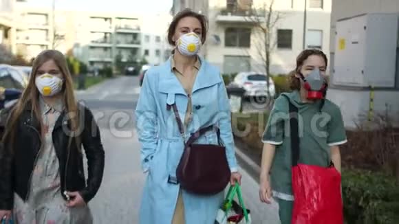 年轻妇女和两个十几岁的孩子沿街蒙面冠状病毒流行期间的杂货店购物视频的预览图