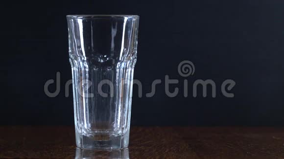 黑色背景上的玻璃把水倒进杯子里透明容器纯净水视频的预览图