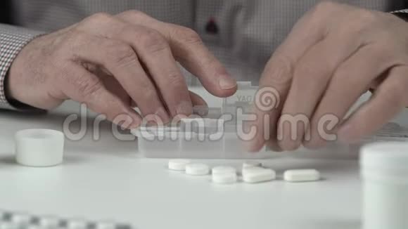 老人皱巴巴的手把白色的小药丸放在容器里视频的预览图