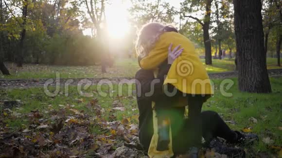 秋天的公园迷人的年轻母亲和一个年轻迷人的小女儿在秋天的花园里玩得很开心视频的预览图