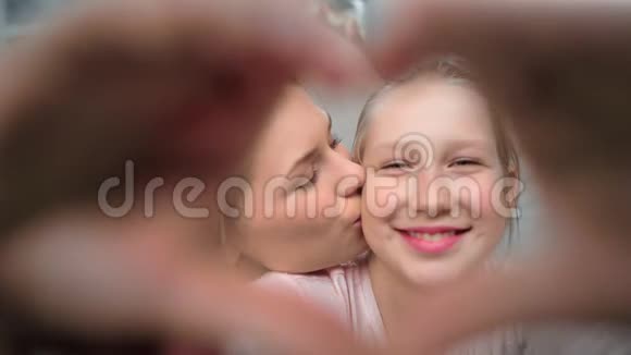 漂亮的年轻妈妈和可爱的少女接吻用手做心脏手势视频的预览图