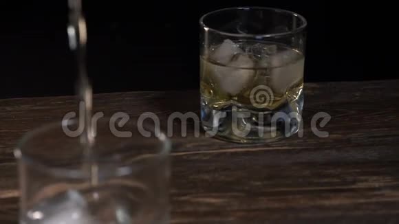 变模糊将金麦芽威士忌倒入装有冰块的玻璃杯中视频的预览图