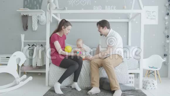 可爱的宝宝和父母坐在床上跳舞视频的预览图