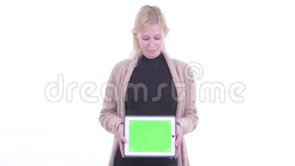 一位年轻的金发碧眼的孕妇正在用数码平板电脑说话视频的预览图