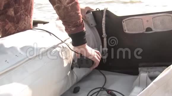 一个雄性渔夫用一个压气机在岸上充气一艘橡皮充气船准备从一艘船上在湖上钓鱼视频的预览图