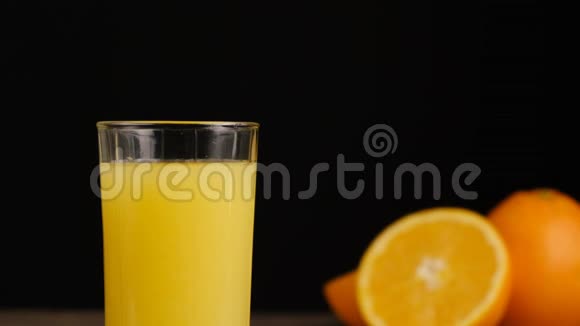 特写冰块落在一杯橙汁或柠檬汁中橘子呈黑色背景视频的预览图