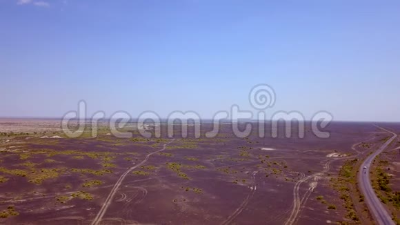 在干旱的沙漠中间的一条空路上驾驶汽车的鸟瞰图视频的预览图