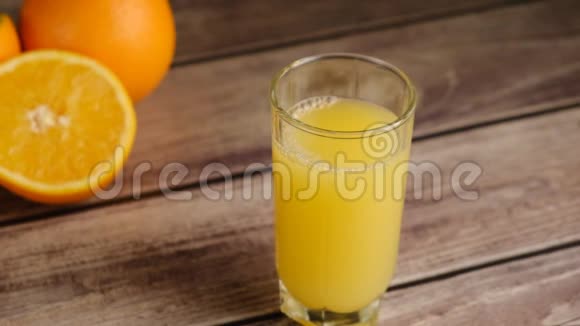 冰块上的俯视图落在一杯橙汁或柠檬水和橘子放在木桌上视频的预览图