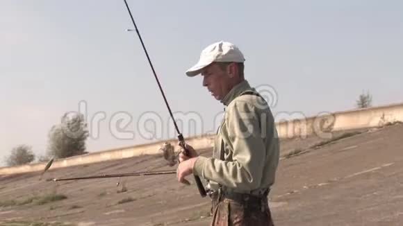 一个雄性渔夫在岸上收集纺棒把它们放进船里准备钓鱼视频的预览图